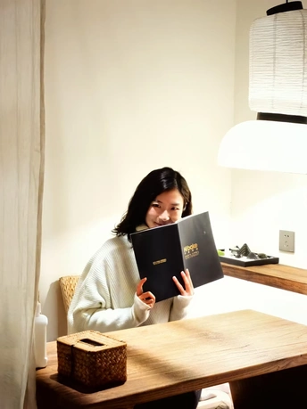 一个年轻女子在一个有灯的桌子旁读书