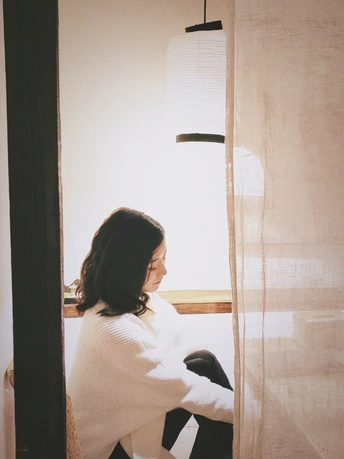 一个坐在窗户边的白色椅子旁边的女人