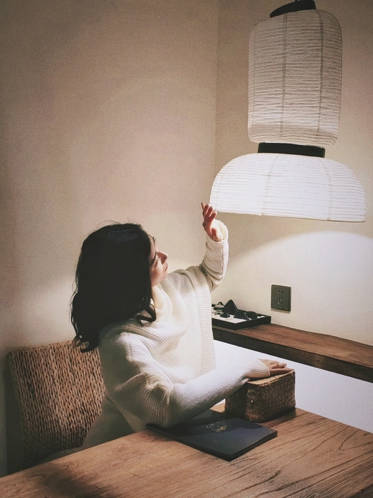 一个年轻女子坐在一个有灯的房间里的一张桌子旁