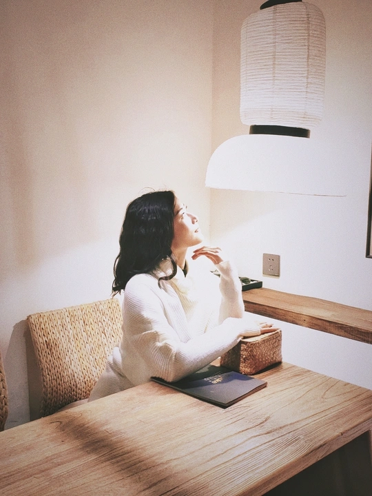 一个坐在木制桌子旁的女人 桌子上放着一本书和咖啡。