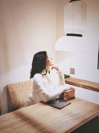 一个坐在木制桌子旁的女人 桌子上放着一本书和咖啡。