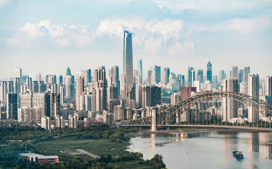 一座大型城市的天际线 高耸的建筑物和一座横跨河流宽度的桥。