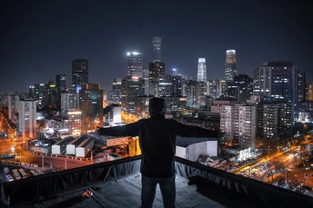 一个站在建筑物屋顶上 凝视着夜晚城市天际线的男人