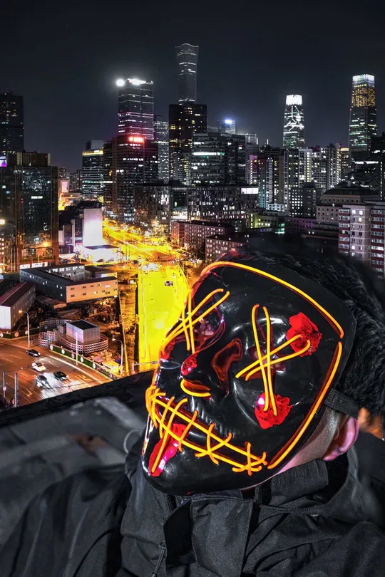 夜晚屋顶上戴口罩的男子与城市背景