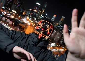 一个人在夜晚的城市前举起双手捂住脸