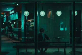 晚上的暗室 人们坐在桌子旁 一个人坐在长椅上