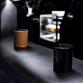 一个黑色的酒吧 有一个亮着的架子 柜台上放着一个咖啡杯 另一个杯子放在柜台上