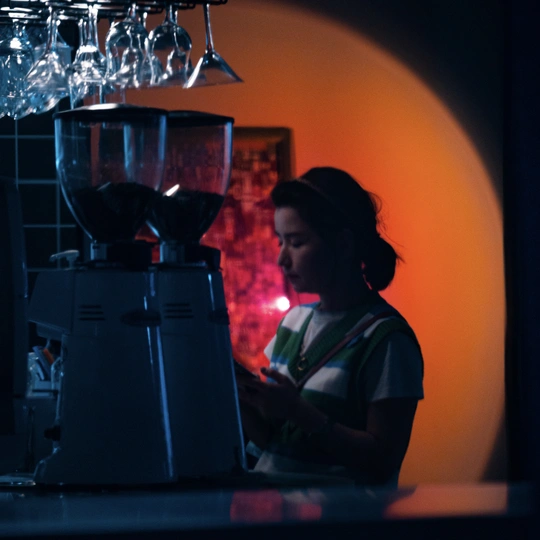 一个年轻的女人站在一个有搅拌机的房间的柜台旁