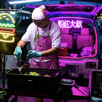 一个穿着围裙和手套的男人在汽车后备箱里做饭