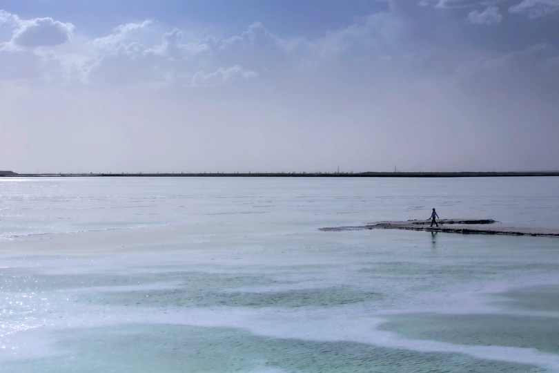 一个人站在沙滩上 水中有冰 在蓝色的天空中。
