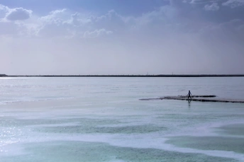一个人站在沙滩上 水中有冰 在蓝色的天空中。
