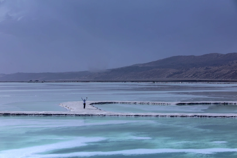 一个站在覆盖着冰的蓝色湖上的男人