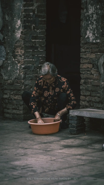 一位老人坐在长椅上 而一位女士跪下来从碗里抓食物