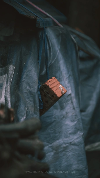 一个穿着蓝色防水布拿着砖头的男人