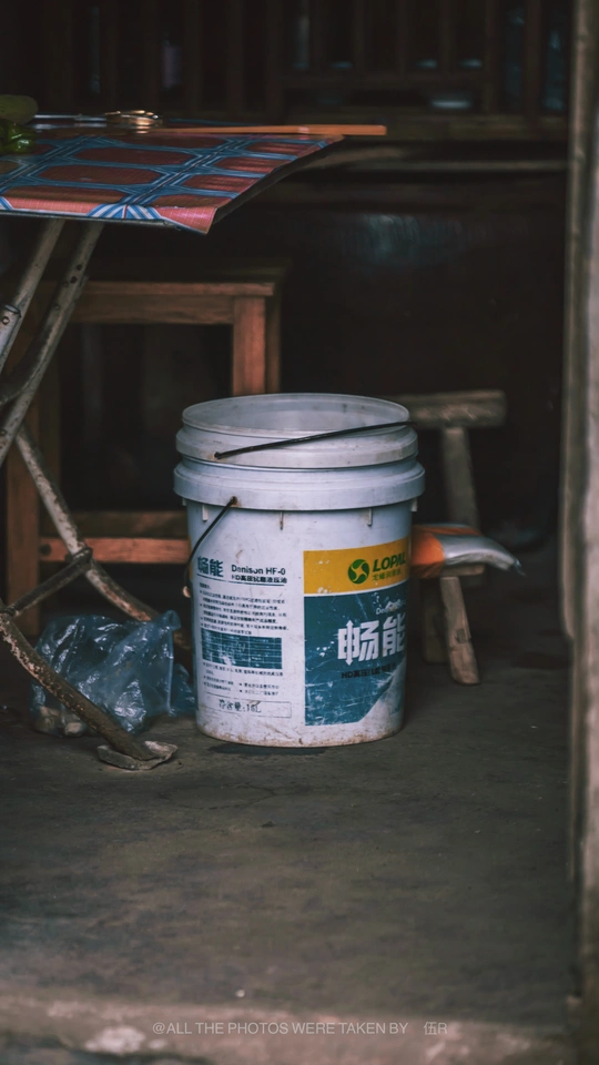 一个放在伞下的白色水桶 旁边是一张木桌