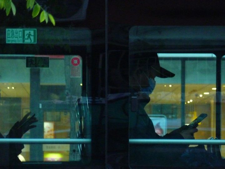 晚上在公交车上的一个男人和一个女人正在看手机