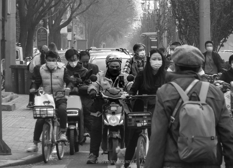 一张黑白照片 人们骑自行车和摩托车。