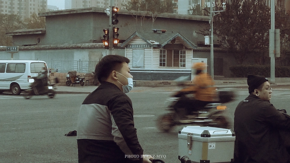 一个戴口罩的男子骑自行车穿过城市街道