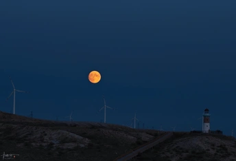 月亮升起在山顶的灯塔上
