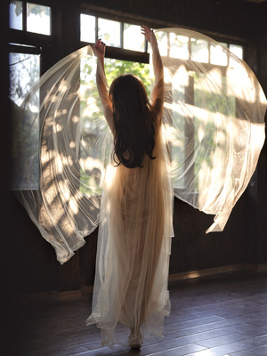 一个穿着带翅膀的白色连衣裙的年轻女子在灯光昏暗的房间里跳舞
