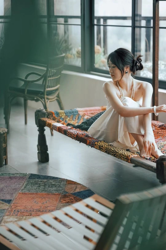一个年轻女子坐在靠近窗户的钢琴旁