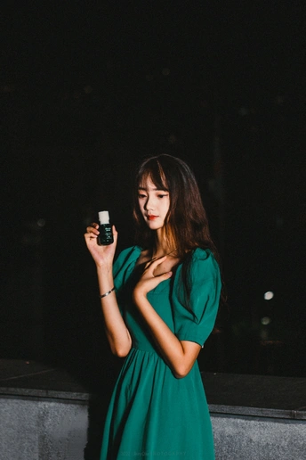一个穿着绿色连衣裙的年轻女子拿着手机在拍照
