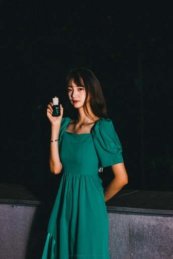 一个穿着绿色连衣裙拿着手机的年轻女子
