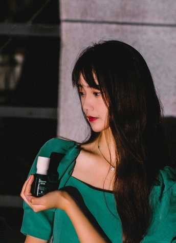 一个穿着绿色连衣裙的年轻女子拿着一个瓶子