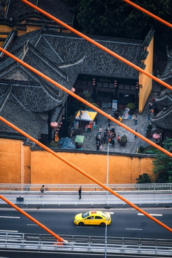 一辆黄色汽车在建筑物旁边的一条街道上行驶