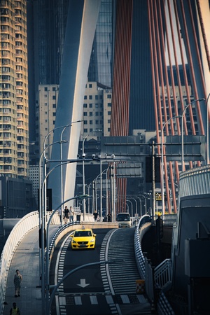 城市中行驶的黄色出租车 桥上有很多建筑物。