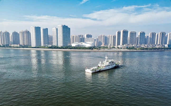 一艘船航行在大连湾港码头附近海面上