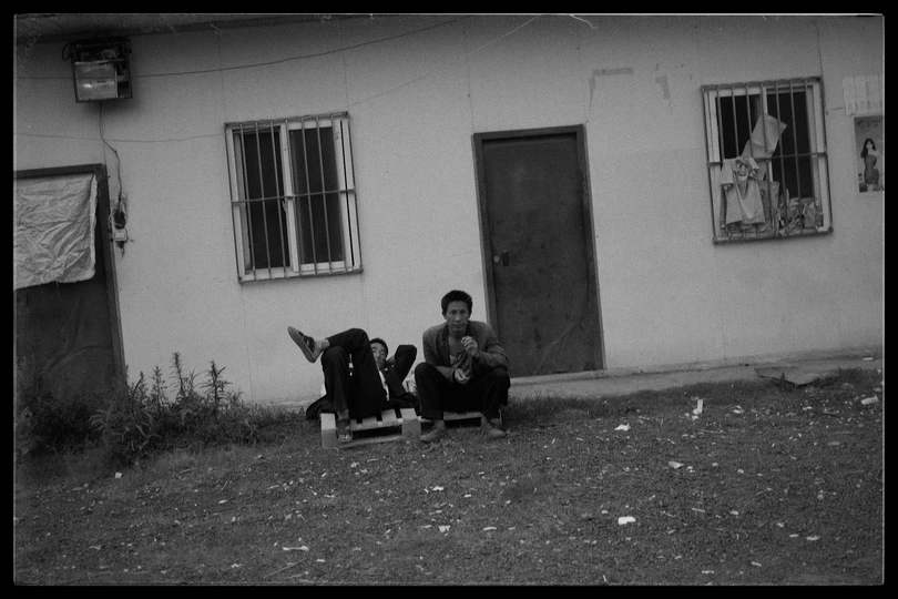 一个小男孩和一个小女孩坐在街上一栋楼房前的椅子上。