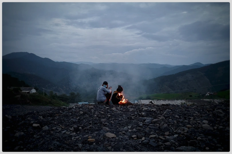 坐在篝火旁的夫妇 背景是山脉。