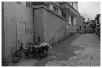 一个人在街头卖水果 旁边坐着一个男孩 一个黑白镜头