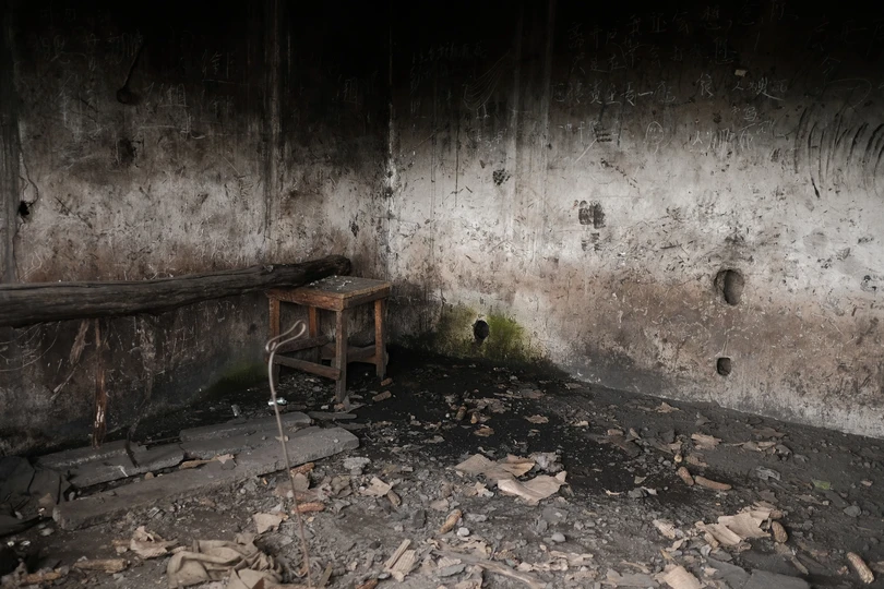 一把椅子和一张桌子坐在房间的中央 地板上有瓦砾。