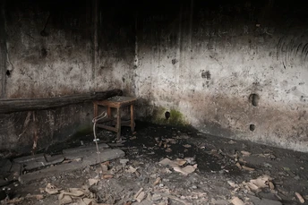 一把椅子和一张桌子坐在房间的中央 地板上有瓦砾。