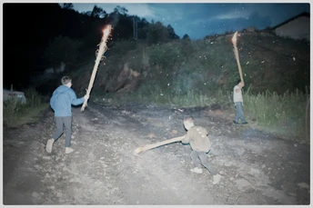 夜晚 一个男孩站在一个拿着燃烧木棒的男子旁边