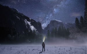 一个人站在白雪皑皑的山上仰望星空 星星闪烁 手拿一盏火炬。