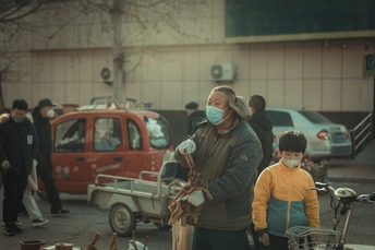 一个戴口罩的男子在城市停车场带着一个孩子走路