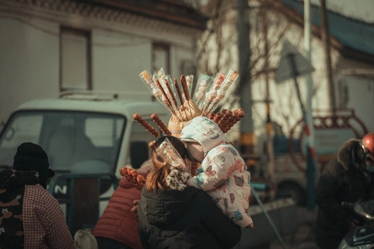 一位女子举着双手过头 走在一条街道上 背景中还有其他人。