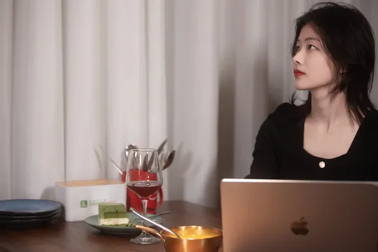 一位女性坐在桌子旁 正在查看电脑。