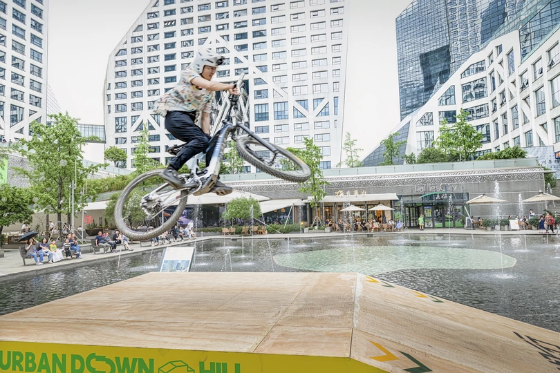 一个滑板男孩在城市中的喷泉上跳过一个水坝。