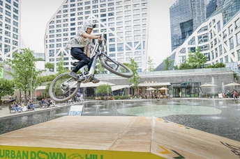 一个滑板男孩在城市中的喷泉上跳过一个水坝。