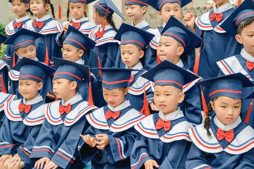 一群戴着蓝色帽子、穿着蓝色长袍的孩子在毕业典礼上的照片