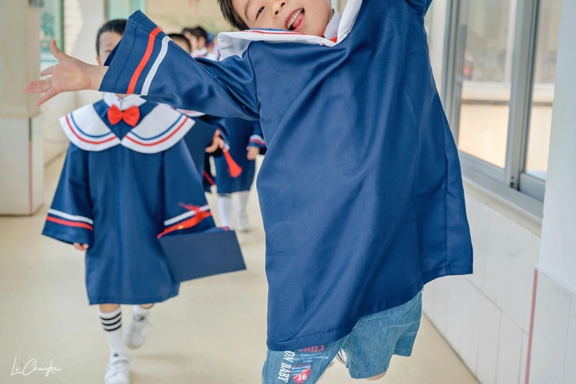 一个穿着蓝色中国校服的小男孩正在教室里和其他孩子玩耍