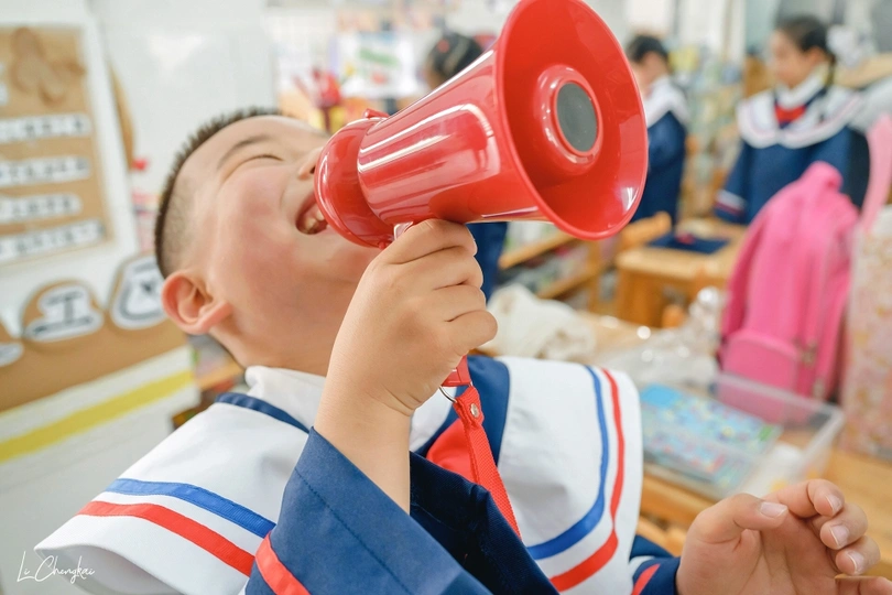 小学教室里一个拿着红色扩音器的小男孩