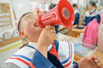 小学教室里一个拿着红色扩音器的小男孩