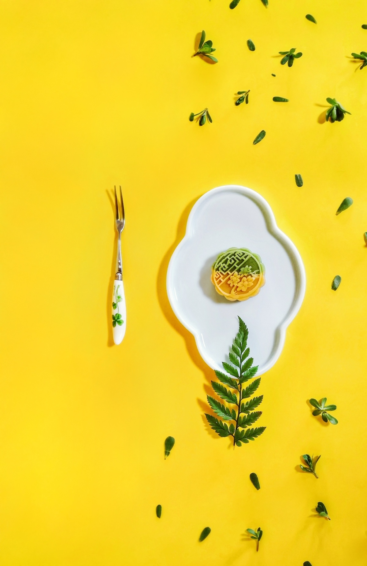 一个带有意大利面的白色盘子 一个叶片和一把叉子 背景为黄色。