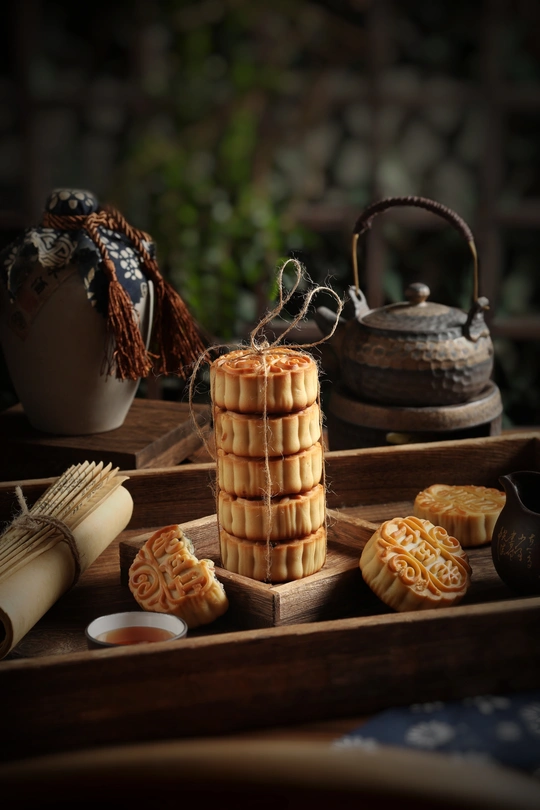 一个木制桌子 上面放着一个托盘 托盘上放着一些小甜点 还放着茶。