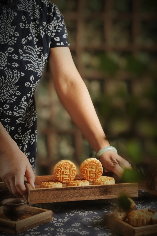 一位女士手拿一个小木托盘 托盘上放着一些像橙子形状的饼干。